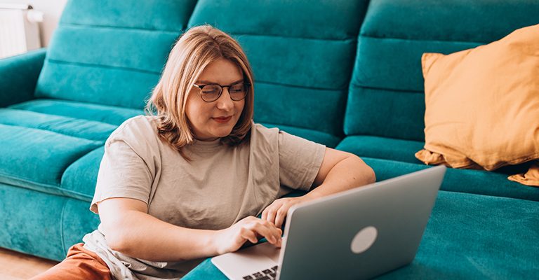 woman propped against the sofa using her laptop