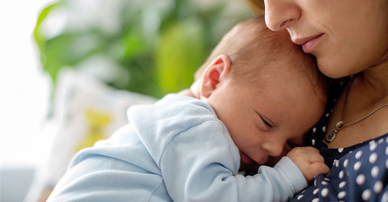 a newborn snuggled with his mother