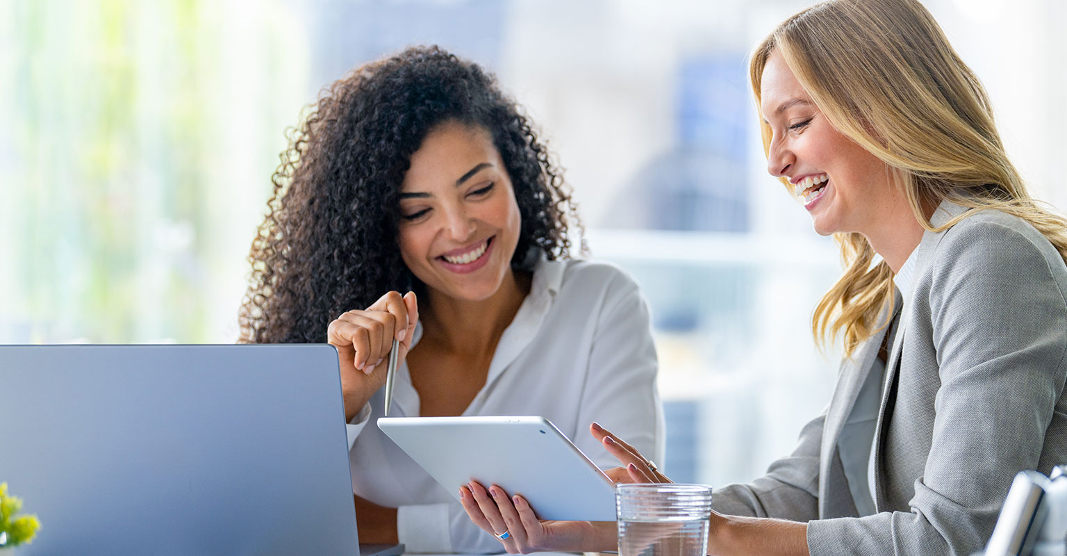 two women reviewing documents on iPad