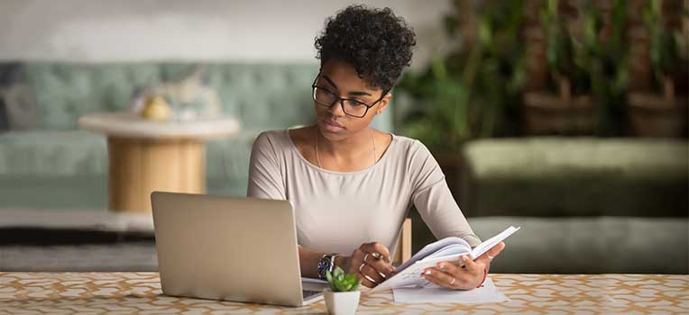 woman reviewing books and laptop for information on egg freezing