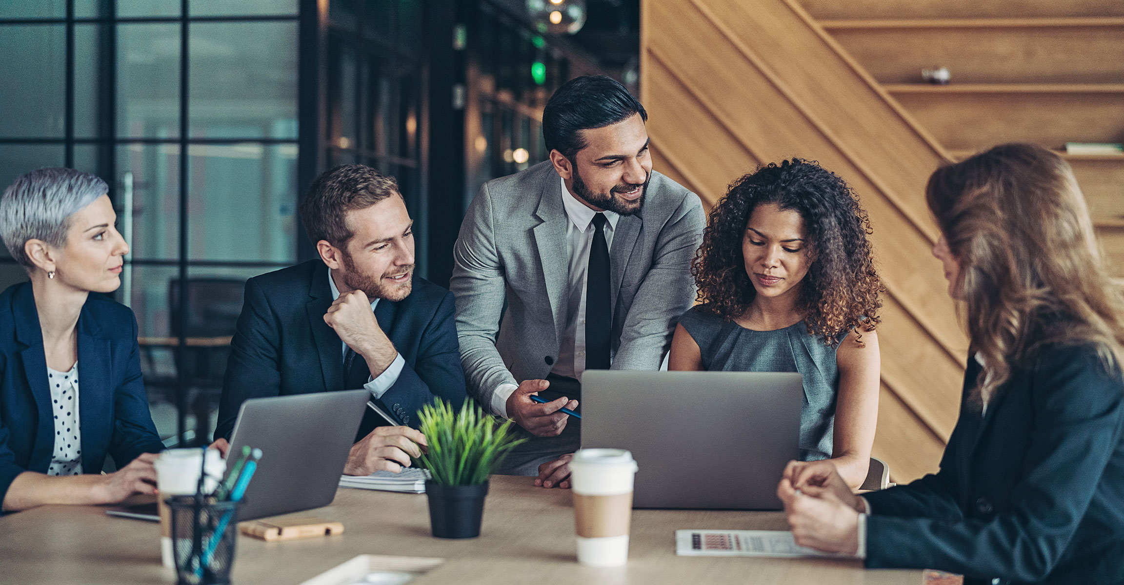 group of colleagues working together at a conference table with their laptops