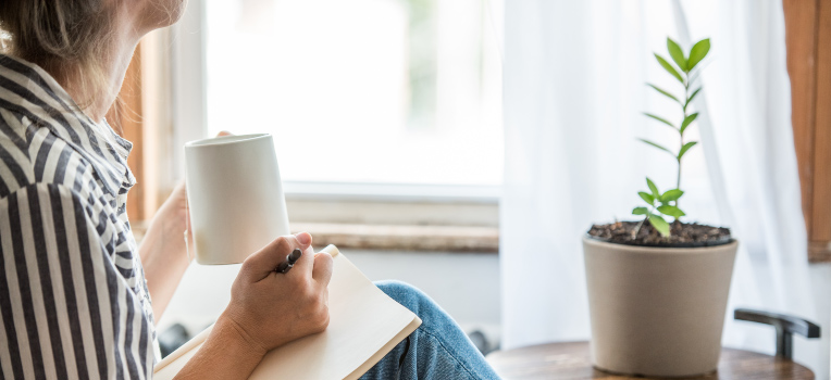 woman journaling seated by the window