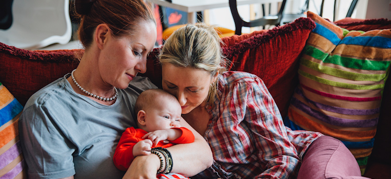 female couple snuggling their baby