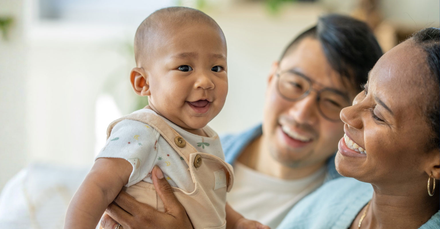 happy baby held up by parents
