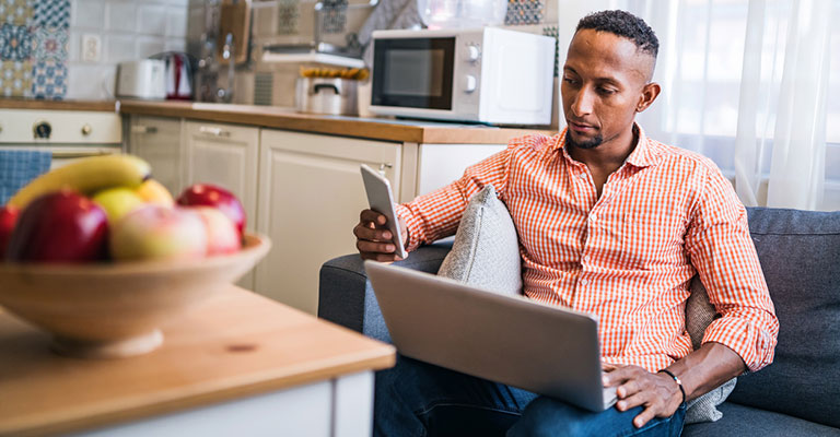 man looking at phone and laptop