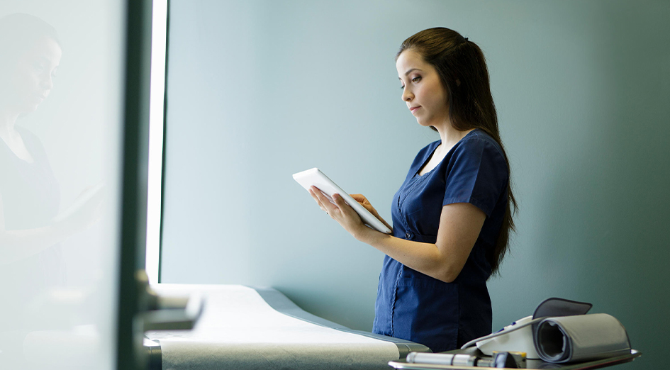 nurse looking at tablet in exam room