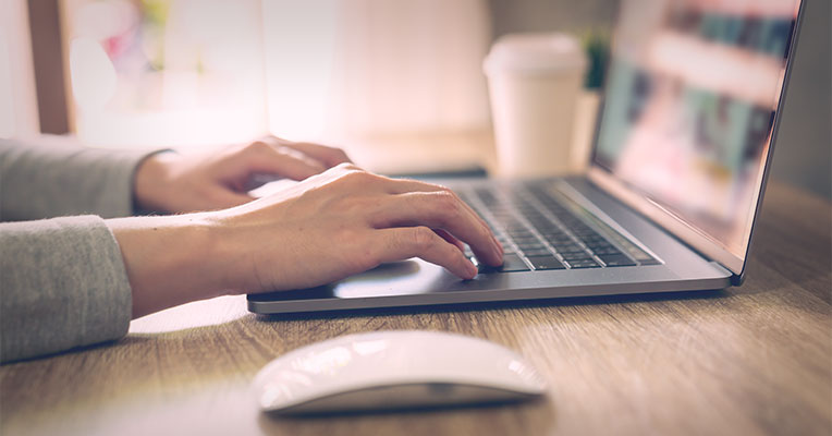 focused shot of hands typing on laptop