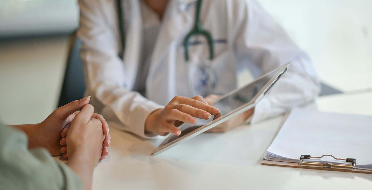 closeup photo of the hands of patient and doctor reviewing ipad