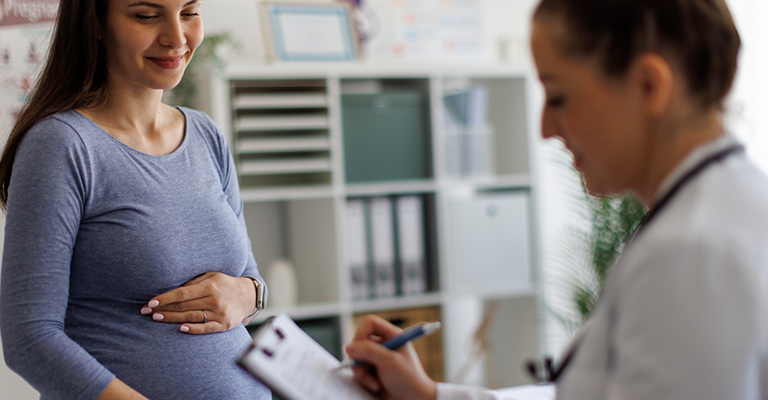 a smiling pregnant woman talking with her doctor