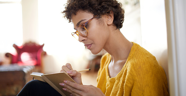 seated woman with glasses journaling