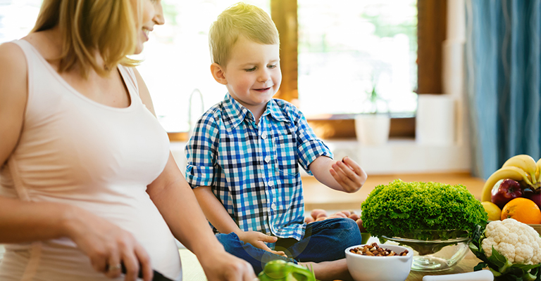 woman with young son in the kitchen preparing a meal