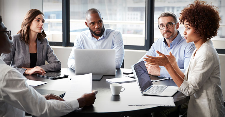 employees with laptops around a conference table