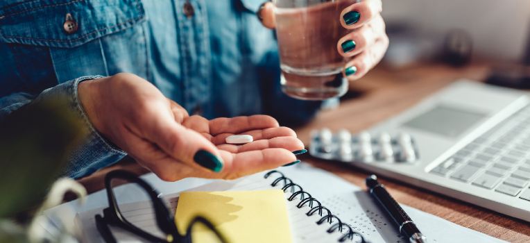 photo of someone about to take medication with a glass of water