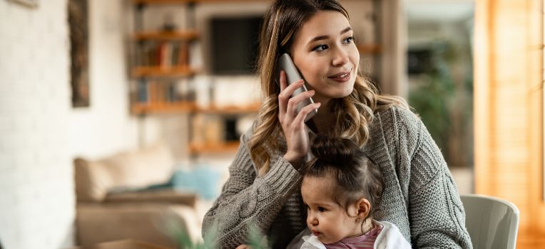 woman with baby in lap talking on the phone