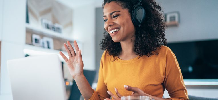 waving woman with headphones on a Zoom call