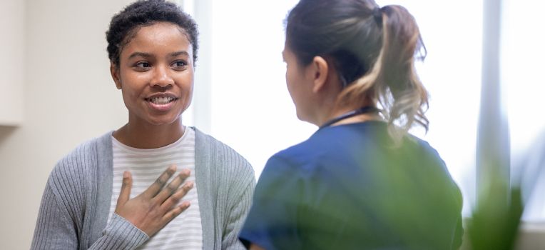 woman with her hand on her heart, talking with clinician