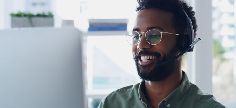 smiling employee with headset helping patients over the phone