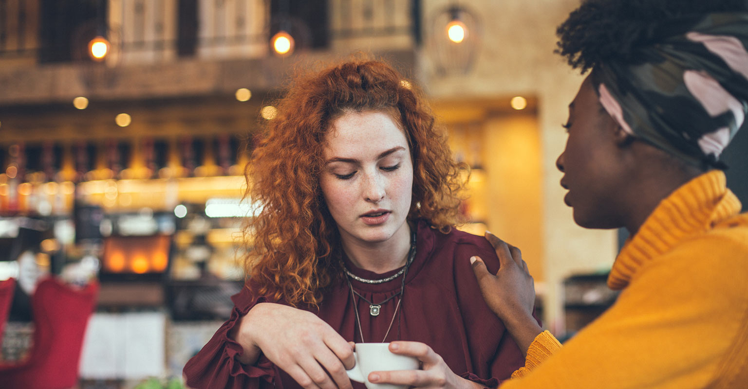 woman comforting friend at cafe
