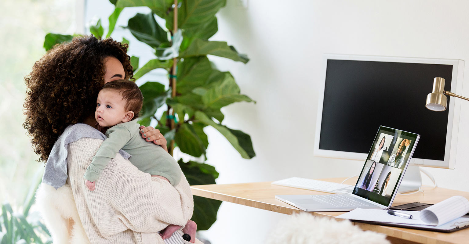 woman holding infant during remote work video call
