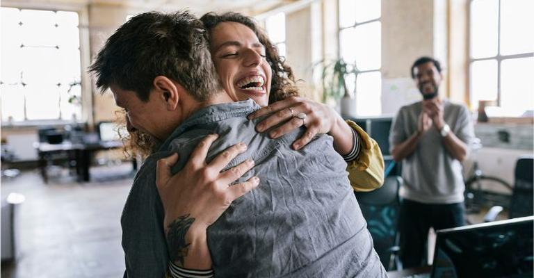 two colleagues giving a congratulatory hug
