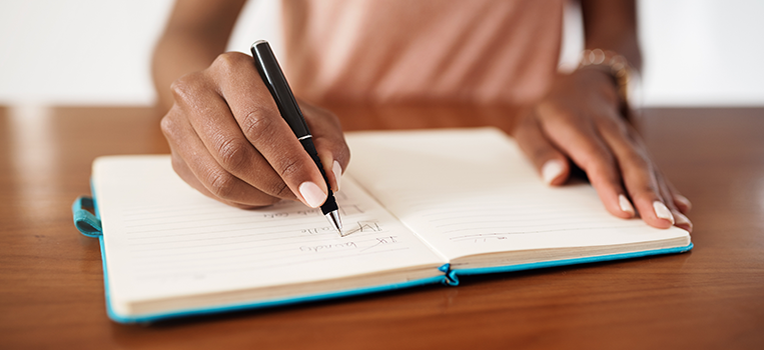 woman's hands taking notes in notebook