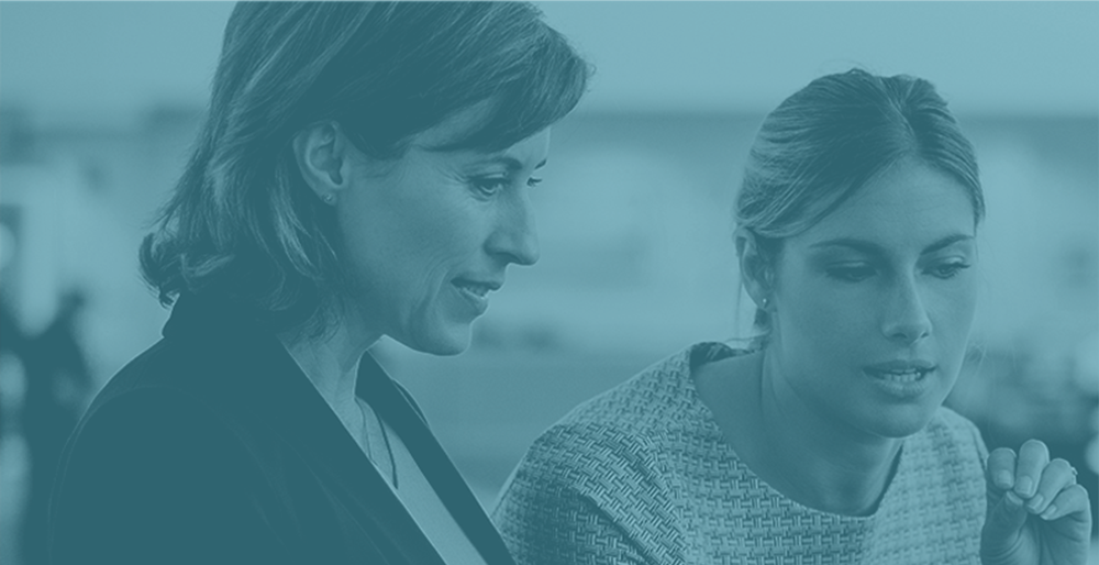 two professional women reviewing something in office setting