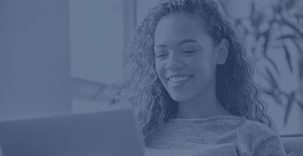 smiling woman viewing laptop on blue background