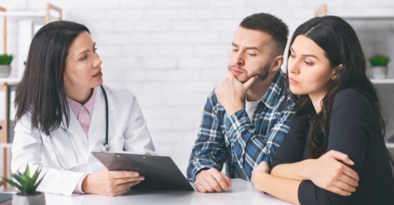 doctor showing clipboard to two patients